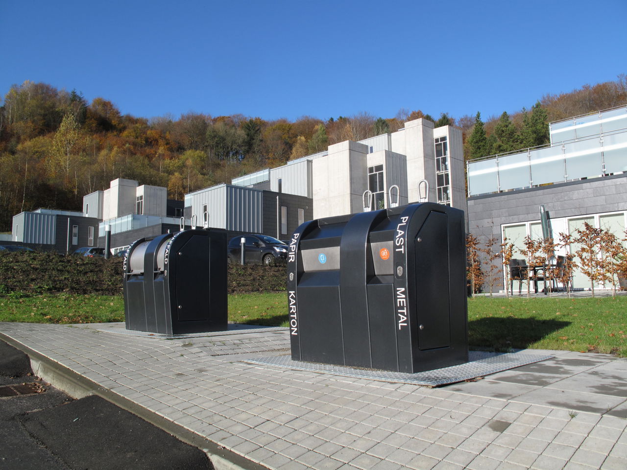 Moderne nedgravede affaldsbeholdere i fællesområde ved nybyggeri i kuperet terræn